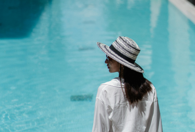 Woman sitting by pool with hat